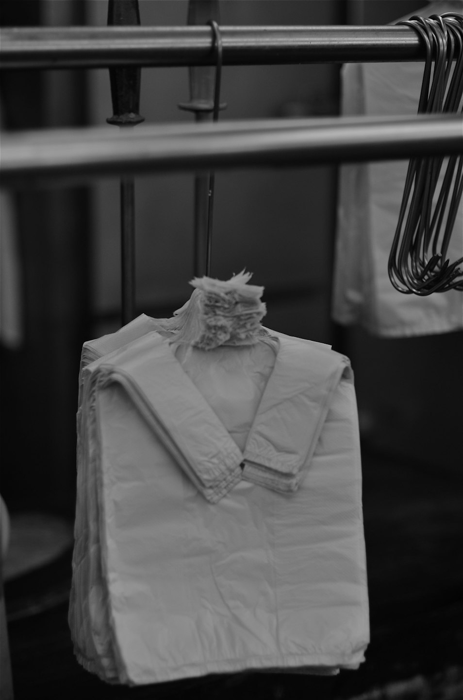White plastic shopping bags stacked on a metal rod.