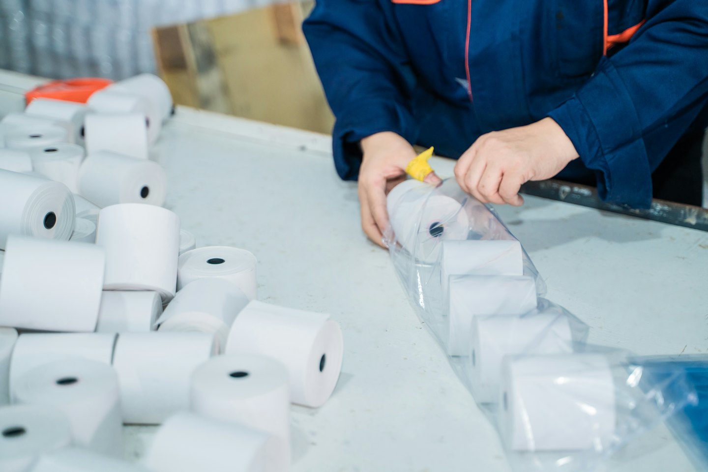 Worker packing thermal paper rolls into a plastic bag.