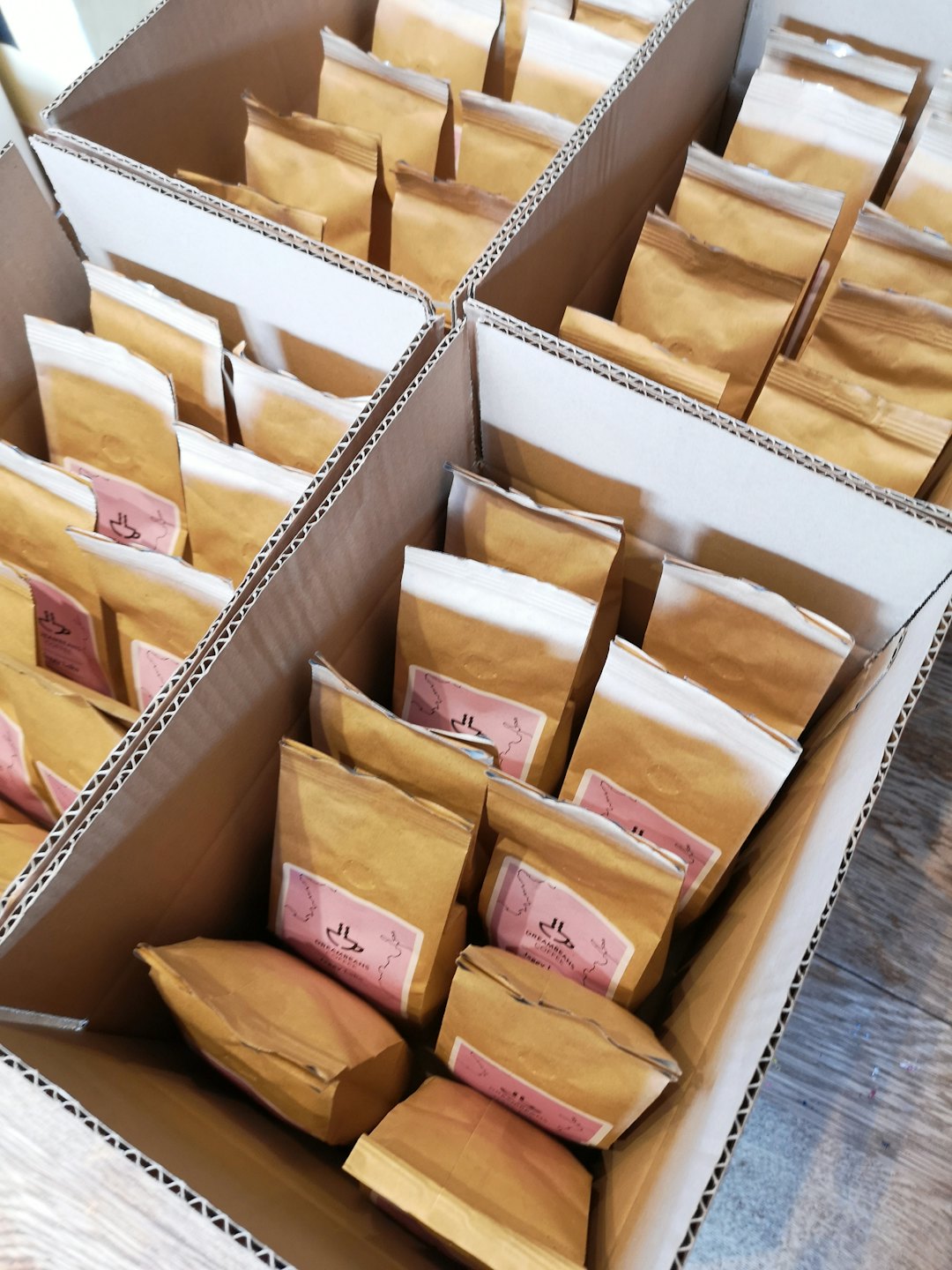 Kraft paper bags sealed with pink stickers in shipping boxes.
