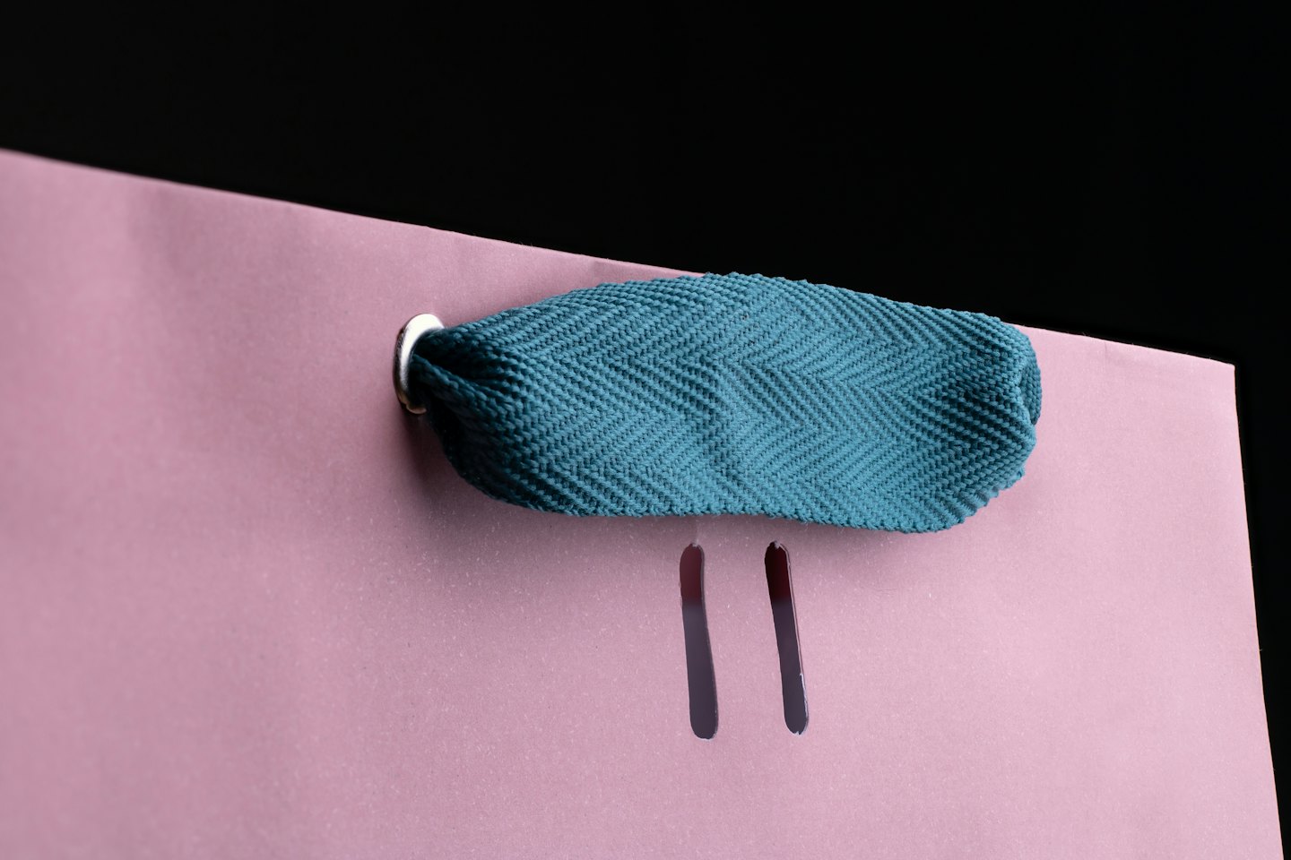 Pink shopping bag with teal woven handle and silver eyelet.