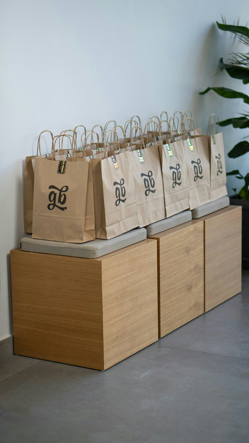 Brown paper bags with black logos on wooden benches.