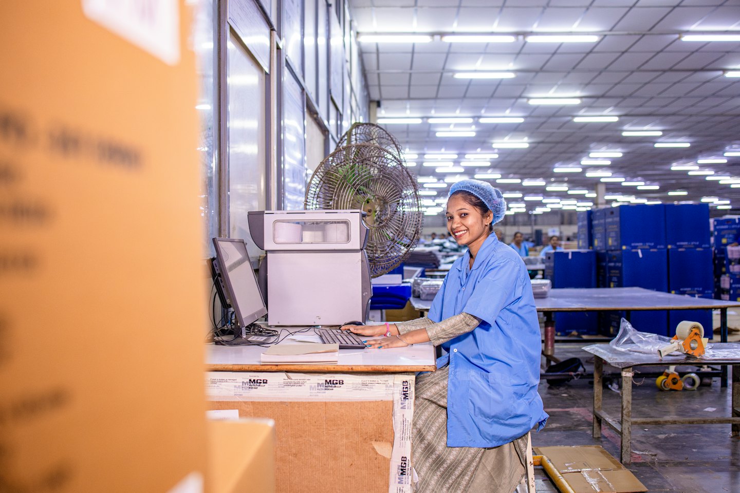 Woman in uniform operating a computer in a factory.